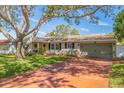 Inviting single-story home with a well-manicured lawn and a large shade tree, complete with an attached garage at 13481 100Th Ave, Seminole, FL 33776