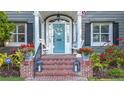 Inviting front porch with brick steps, white columns, porch swing, and a teal front door with a floral wreath at 145 14Th Ne Ave, St Petersburg, FL 33701