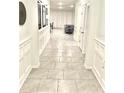 Inviting hallway with stylish wainscoting and neutral tile flooring leading to the living spaces at 33298 Major Oak Dr, Wesley Chapel, FL 33545