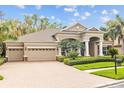 Attractive home exterior with a brick driveway, three-car garage, and lush landscaping at 3543 Watermark Dr, Wesley Chapel, FL 33544