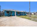 Attractive single-story home featuring a blue exterior, a well-kept driveway, and mature trees at 14040 Miramar Ave, Madeira Beach, FL 33708