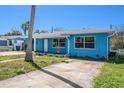 Inviting one-story home painted blue, accented by a tidy lawn and a clear blue sky at 14040 Miramar Ave, Madeira Beach, FL 33708