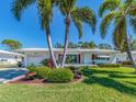 Inviting single-story home with lush landscaping and mature palm trees creating a tropical ambiance at 14173 90Th Ave, Seminole, FL 33776