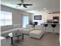 Bright open-concept living room featuring modern furnishings, a ceiling fan and view into the kitchen at 31888 Treasure Dock Isle, Wesley Chapel, FL 33545