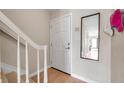Home entryway showcasing stairs and mirror; door with sign 