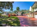 Elegant home featuring a red brick driveway, lush lawn, and classic architecture with a green tile roof at 802 Druid S Rd, Clearwater, FL 33756