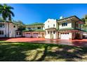 Rear view of a beautiful home featuring a brick driveway, multiple garage doors and a lush green lawn at 802 Druid S Rd, Clearwater, FL 33756