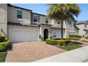 Inviting two-story townhome showcases a brick driveway, attached garage, and manicured front yard with a mature palm tree at 10106 Corso Milano Dr, Tampa, FL 33625