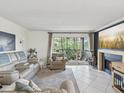 Cozy living room with fireplace, tile floors, and access to a balcony with chairs and plants at 2400 Feather Sound Dr # 1118, Clearwater, FL 33762