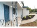 Inviting front porch featuring a stylish blue door, tiled flooring, and decorative metal railings at 2610 E Yukon St, Tampa, FL 33604