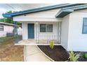 Inviting front porch featuring a stylish blue door, tiled flooring, and decorative metal railings at 2610 E Yukon St, Tampa, FL 33604