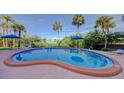 Inviting pool with clear blue water, surrounded by palm trees and lush landscaping, perfect for relaxation and enjoyment at 50 Harbor View Ln # 21, Belleair Bluffs, FL 33770