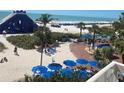 Expansive beachfront area with recreational amenities, palm trees, and a lively crowd enjoying the sunny weather at 5500 Gulf Blvd # 4226, St Pete Beach, FL 33706