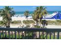 Balcony view of palm trees, sandy beach, Gulf Coast waters, a large water slide, and beach chairs at 5500 Gulf Blvd # 4226, St Pete Beach, FL 33706