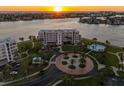 Breathtaking aerial view of a condo complex with a pool, circular driveway, and stunning waterfront views at sunset at 8040 Sailboat Key S Blvd # 402, St Pete Beach, FL 33707