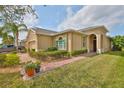 Close-up of tan home with well-manicured lawn, brick walkway and tropical landscaping at 807 Chipper Dr, Sun City Center, FL 33573