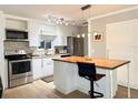 Modern kitchen features white cabinets, stainless appliances, and a butcher block island at 8711 Plum Ln, Temple Terrace, FL 33637