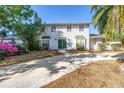 Charming two-story home features a white brick exterior, green front door, and a spacious driveway at 13982 Whisperwood Dr, Clearwater, FL 33762
