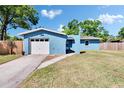 Quaint one-story home with a white garage door, blue exterior, and an arched entryway at 2035 Ronald Cir, Seffner, FL 33584
