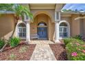 Inviting front entrance featuring a charming blue double door, brick walkway, and manicured garden at 2905 Hillside Ramble Dr, Brandon, FL 33511