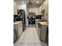 Galley kitchen featuring stainless steel appliances, tile floors, and lots of cabinet space at 3120 Dole St, Holiday, FL 34691