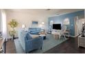 Bright living room featuring stylish blue furniture, dark floors, and coastal decor at 401 Dorchester Pl # 55, Sun City Center, FL 33573