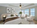 Sun-filled main bedroom featuring a tray ceiling, stylish decor and comfortable seating area at 5014 Sterling Manor Dr, Tampa, FL 33647