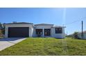 Attractive single-story home featuring a modern design, well-manicured lawn, and a spacious driveway leading to a two-car garage at 5166 Deltona Blvd, Spring Hill, FL 34606