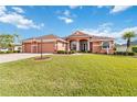 Beautifully landscaped single-story home with a manicured lawn, brick driveway, and charming front facade at 5444 90Th Avenue E Cir, Parrish, FL 34219