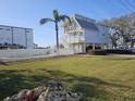 Two-story stilt house on grassy lot, fenced in with a palm tree. Clear, sunny day with a blue sky at 7400 140Th St, Seminole, FL 33776