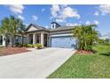 Landscaped single-Gathering home featuring a blue garage door and lush tropical landscaping at 8100 Olive Brook Dr, Wesley Chapel, FL 33545