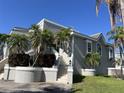 Attractive light grey exterior of a home with white trim, tiered landscaping, and tropical palms under a blue sky at 816 Ponce De Leon Dr, Tierra Verde, FL 33715