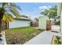 Fenced backyard with a lush green lawn and walkway leading to a private outdoor space at 10306 Green Grove Pl, Tampa, FL 33624