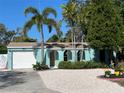 Charming home with a well-manicured front yard featuring tropical plants, flowers, and a concrete driveway at 1754 Patricia Ave, Dunedin, FL 34698