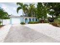 Charming blue home with palm trees, white rock landscaping, and an attached one car garage at 1754 Patricia Ave, Dunedin, FL 34698
