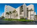 Exterior of a white building with neatly manicured green space and vibrant palm trees at 19111 Vista Bay Dr # 402, Indian Shores, FL 33785