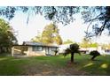 View of the home featuring a front yard with palm trees, and attached carport on a sunny day at 19455 Fort Dade Ave, Brooksville, FL 34601