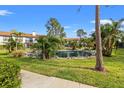 Beautiful pond in a courtyard surrounded by condos with palm trees, lush green grass, and a fountain in the middle at 1986 Pelican Landing Blvd # 1514, Clearwater, FL 33762