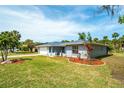 View of the property featuring a lush green lawn, landscape beds, and a two-car garage at 5471 Nimitz Rd, New Port Richey, FL 34652