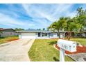 Well-manicured front lawn with palm trees leading to a charming single-story home with a two-car garage at 5471 Nimitz Rd, New Port Richey, FL 34652