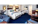 This bedroom has two queen beds, a kitchenette, a chair, and stylish decor at 5500 Gulf Blvd # 2228, St Pete Beach, FL 33706