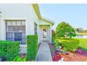 Inviting entryway features a decorative glass door, colorful flowers, and established shrubbery at 9426 Green Needle Dr, New Port Richey, FL 34655