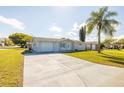 Well-kept single-story home featuring an expansive driveway, lush lawn, and attached garage at 10900 Oakdale Ave, Port Richey, FL 34668