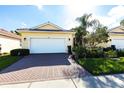 Charming single-story home with a red brick driveway, a two-car garage and lush landscaping at 16106 Amethyst Key Dr, Wimauma, FL 33598