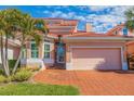Charming home featuring a clay tile roof, two-car garage, brick driveway, and mature landscaping at 218 Sand Key Estates Dr, Clearwater Beach, FL 33767