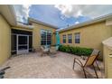 Relaxing outdoor patio features brick flooring, an umbrella-covered table, chair seating, views of the lush, green yard, and a screened-in lanai at 2286 Sifield Greens Way # 2286, Sun City Center, FL 33573