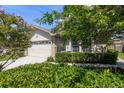 Charming single-Gathering home featuring a manicured lawn, a two-car garage, and a beautifully landscaped front yard with mature trees at 2991 Covewood Pl, Clearwater, FL 33761