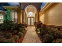 Welcoming front entrance with a brick walkway, manicured plants, and decorative glass double doors at 3198 Thatcher Ln, Tarpon Springs, FL 34688
