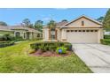 Well-maintained single-story home with green lawn, manicured shrubbery, and an ADT security sign at 3215 Banyan Hill Ln, Land O Lakes, FL 34639