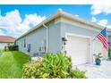 This home's side exterior features a well-maintained lawn, plants, and a two car garage at 4926 Pamplona Ct, Wimauma, FL 33598
